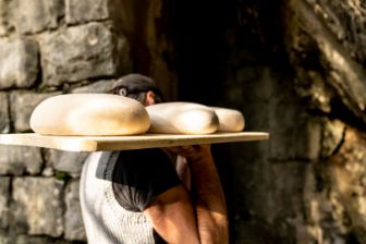 Käser trägt Käselaibe in den Reifungskeller.